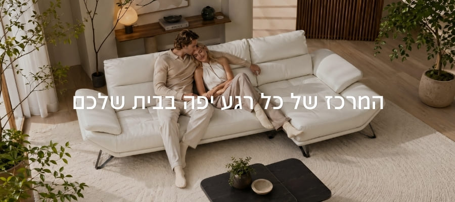 זוג מתחבק על ספת שזלונג יוקרתית בצבע לבן-קרם בסלון מודרני מעוצב. על התמונה מופיע הכיתוב: 'המרכז של כל רגע יפה בבית שלכם'.